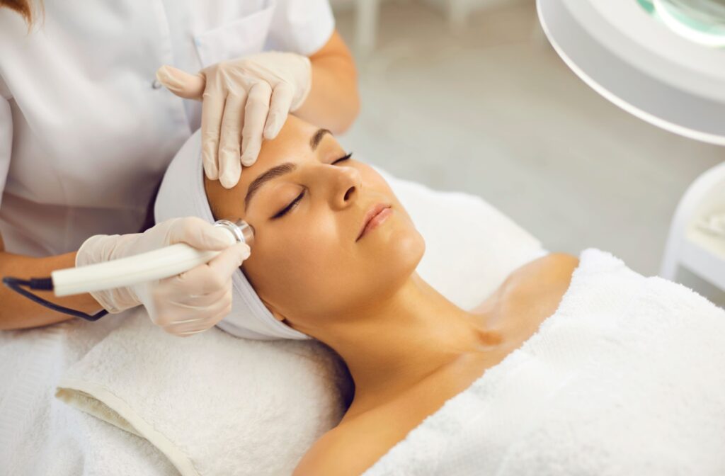 An optometrist uses a device to stimulate the skin around a person's eyes during their dry eye treatment session.
