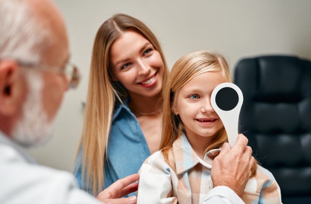 An eye doctor covers a young patient's eye to monitor their vision.