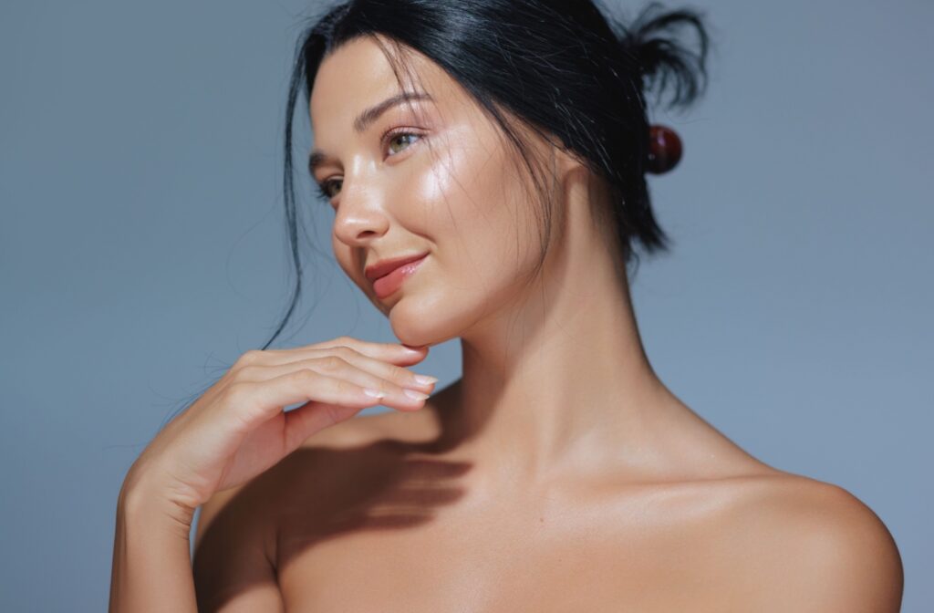 A model with clear skin looks to the side in front of a blue background